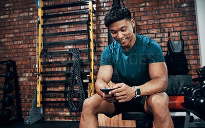 Buy stock photo Cropped shot of a sporty young man using his cellphone at the gym