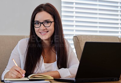 Buy stock photo Shot of a young woman writing notes while working from home