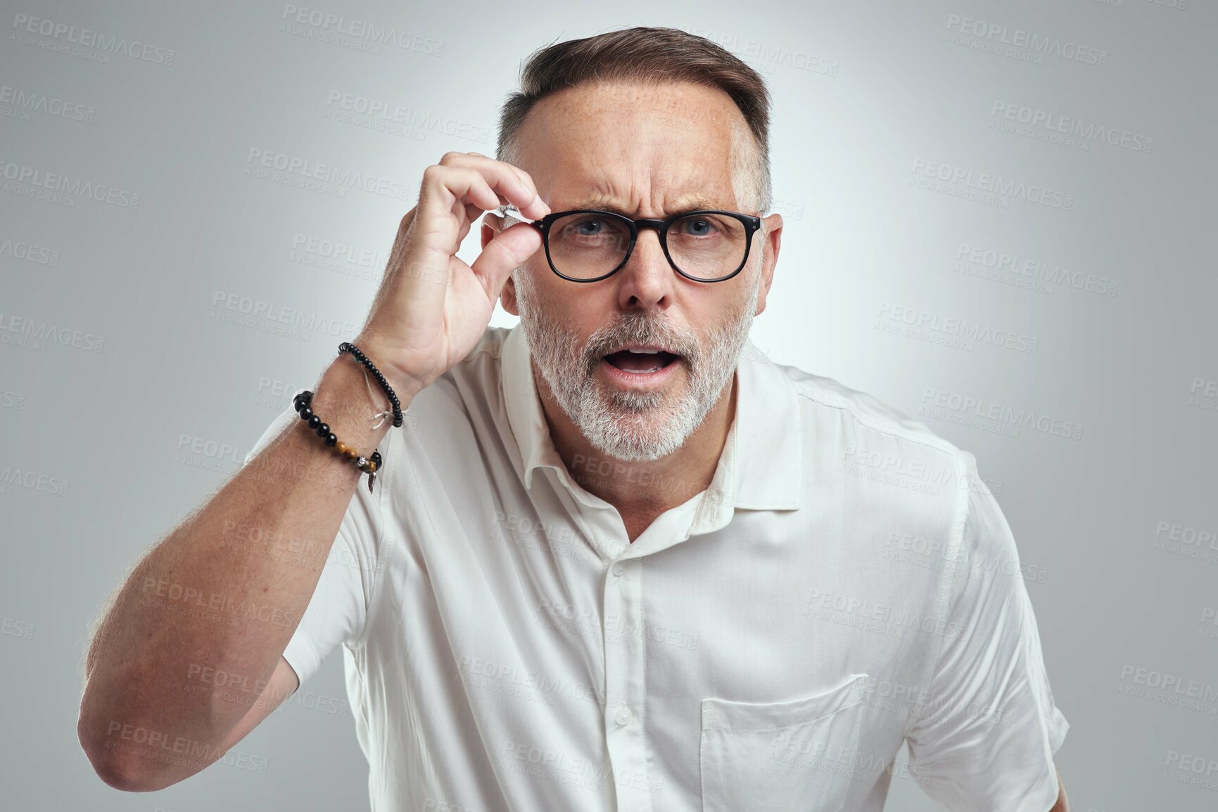 Buy stock photo Studio portrait of a mature man wearing spectacles and looking confused against a grey background