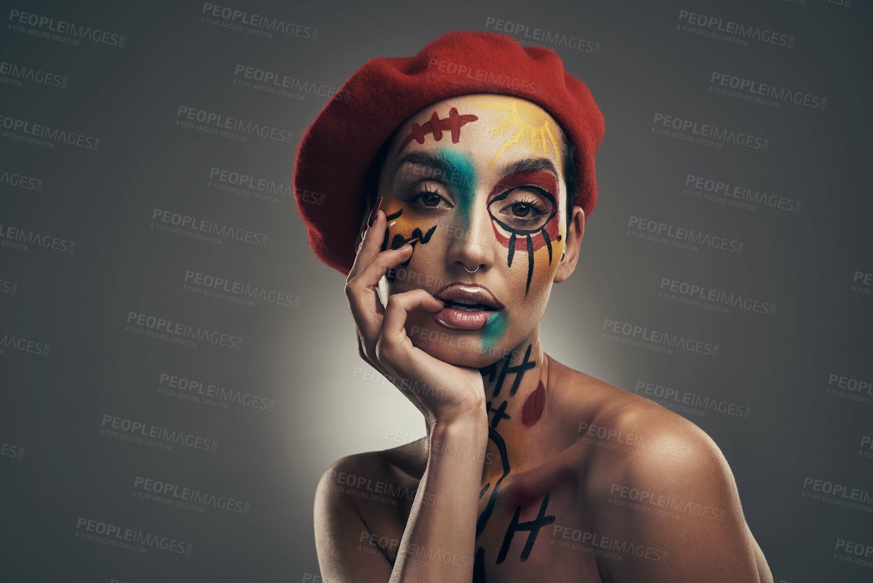 Buy stock photo Studio shot of a young woman posing with paint on her face on a grey background