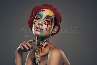 Buy stock photo Studio shot of a young woman posing with paint on her face on a grey background