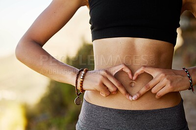 Buy stock photo Cropped shot of a young woman forming a heart shape over her stomach
