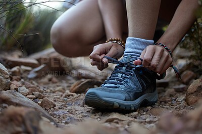 Buy stock photo Cropped shot of an unrecognizable woman typing her laces while out hiking