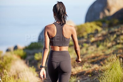Buy stock photo Rearview shot of a sporty young woman walking along a path outdoors