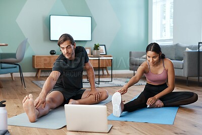 Buy stock photo Full length shot of an athletic young couple stretching in front of a laptop during their workout at home