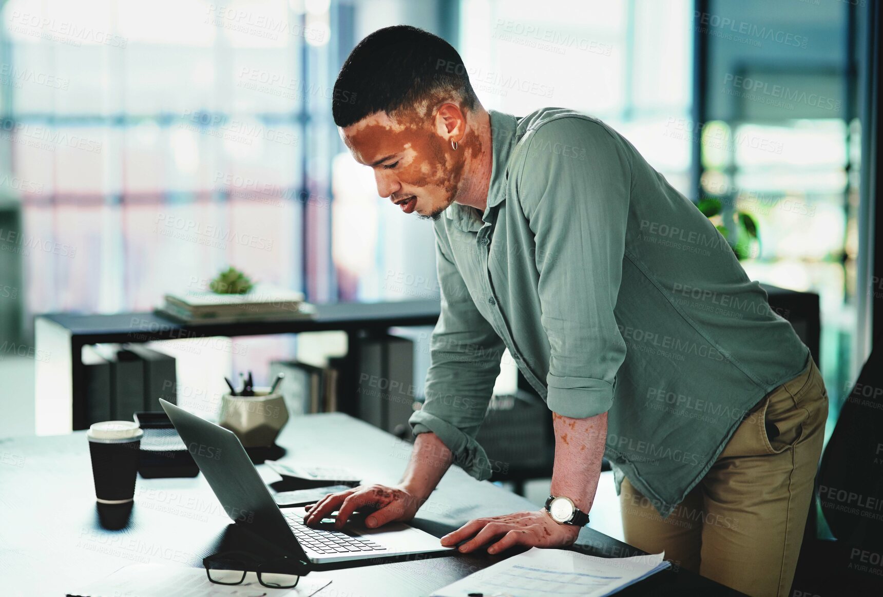 Buy stock photo Shot of a young businessman using a laptop in an office at work