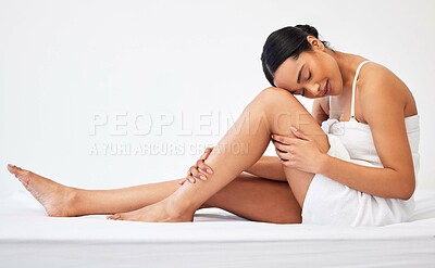 Buy stock photo Shot of a young woman sitting against a white background with a towel wrapped around her body