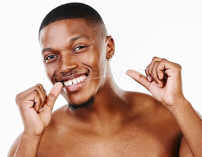 Buy stock photo Studio portrait of a handsome young man flossing his teeth against a white background