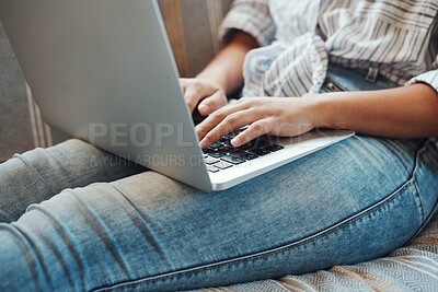 Buy stock photo Cropped shot of an unrecognizable woman using her laptop while relaxing on a sofa at home