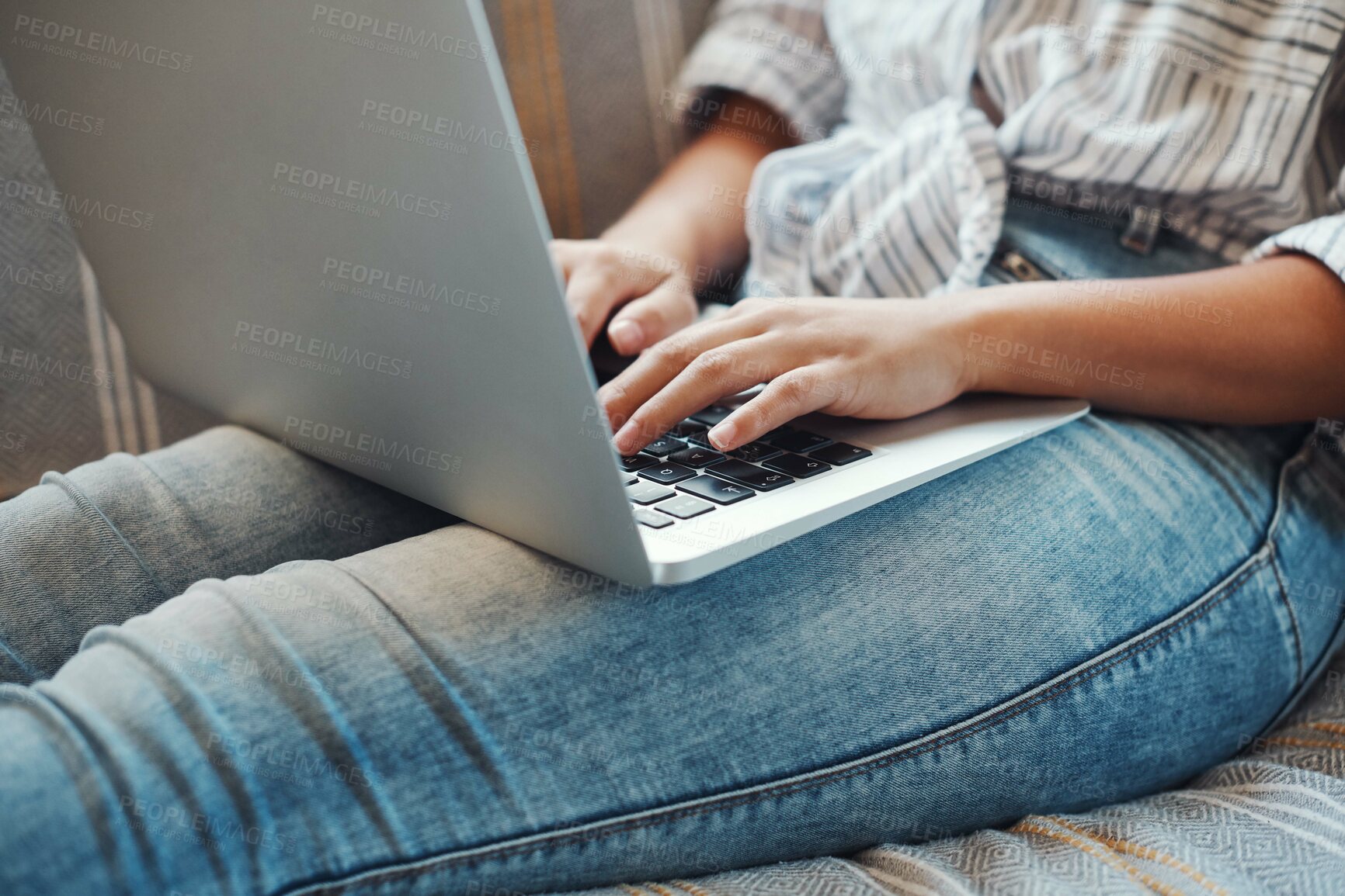 Buy stock photo Cropped shot of an unrecognizable woman using her laptop while relaxing on a sofa at home