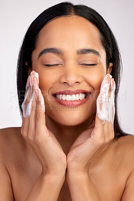 Buy stock photo Happy woman, face and washing for skincare hygiene, cleaning or dermatology against a grey studio background. Female person with smile and soap hands for clean facial treatment, self care or love