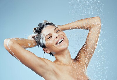 Buy stock photo Studio portrait of an attractive young woman washing her hair while taking a shower against a blue background