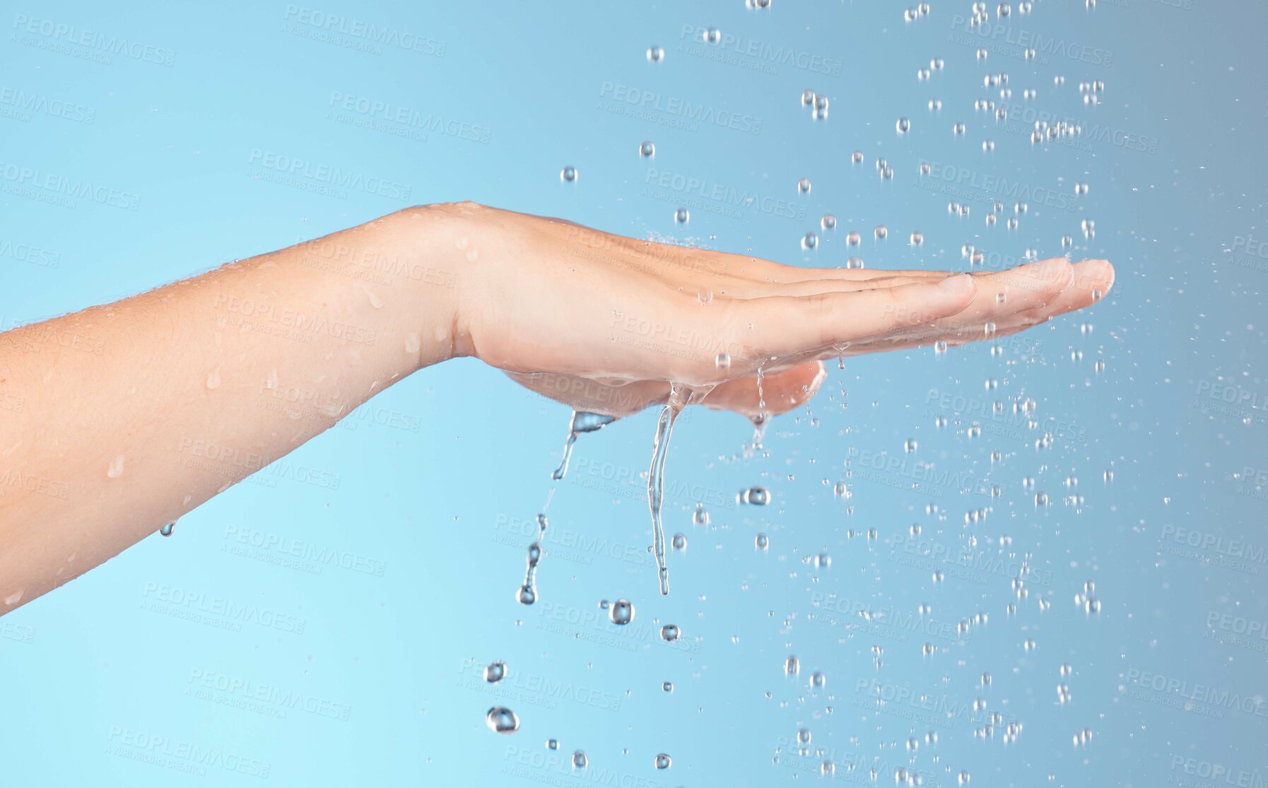 Buy stock photo Woman cleaning hands with water splash, shower and beauty for healthy skincare, personal hygiene and wellness on blue background. Closeup of water drops for washing hands, palm and body in bathroom 