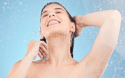 Buy stock photo Shower, water drops and woman in studio for hair care, cosmetics and body cleaning with health promotion in bathroom blue background. Happy woman or model glow with skin care in morning water splash