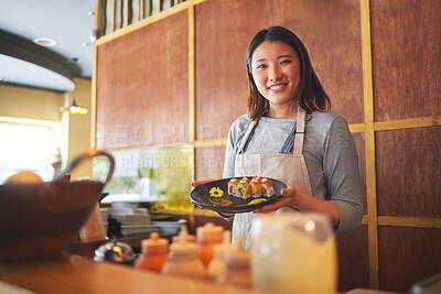 Sushi restaurant, portrait and female waitress with a plate for serving a food order with a smile. Happy, lunch and young Asian server with Japanese recipe or meal at a traditional cuisine cafe.
