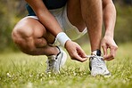 Shoes, tie and a sports person getting ready for a run closeup outdoor during cardio training. Fitness, exercise or workout with an athlete at the start of his marathon on a field of grass in summer