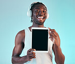 Headphones, tablet and portrait of black man in a studio listening to music, playlist or album. Happy, smile and African male model with digital technology streaming song isolated by blue background.