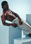 Body, chest and black man relax in studio for wellness, grooming or self care on blue background. Topless, muscle and African male model rpose with cosmetic care, treatment or fine art aesthetic 