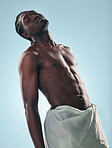 Body, black man and portrait in studio with art, skincare and glow from wellness and confidence. Strong muscle and African male model with creative blue background and relax with power and fitness