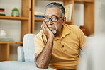 Face, mental health and thinking with a sad old man on a sofa in the living room of his retirement home. Depression, alzheimer or dementia and a senior person looking lonely with memory nostalgia