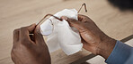 Hands, glasses and cloth for cleaning, closeup and maintenance for lens, frame and eye health in home. Person, fabric and spectacles for optometry, vision and wellness for eyesight at table in home