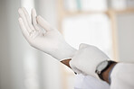 Doctor, pull on and gloves for safety in closeup at hospital for patient, exam or medicare on blurred background. Person, nurse and protection for medical, health or treatment by consulting in clinic