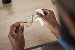 Hands, glasses and fabric for cleaning, closeup and maintenance for dust, frame and eye health in home. Person, cloth and spectacles for optometry, vision and wellness for eyesight at table in house