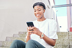 Phone, stairs and young woman in a building networking on social media, mobile app or the internet. Smile, technology and African female person scroll on website with cellphone in a modern office.