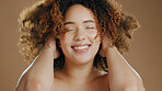 Happy woman, curly hair or natural beauty dermatology for wellness in studio with smile or skin glow. Face, smile or confident biracial female person with skincare cosmetics on a brown background