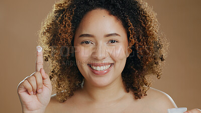Buy stock photo Skincare, black woman and lotion on hand or face for dermatology, beauty or happiness on brown background. Skin, care and happy portrait with cosmetics, cream or product for wellness and confidence