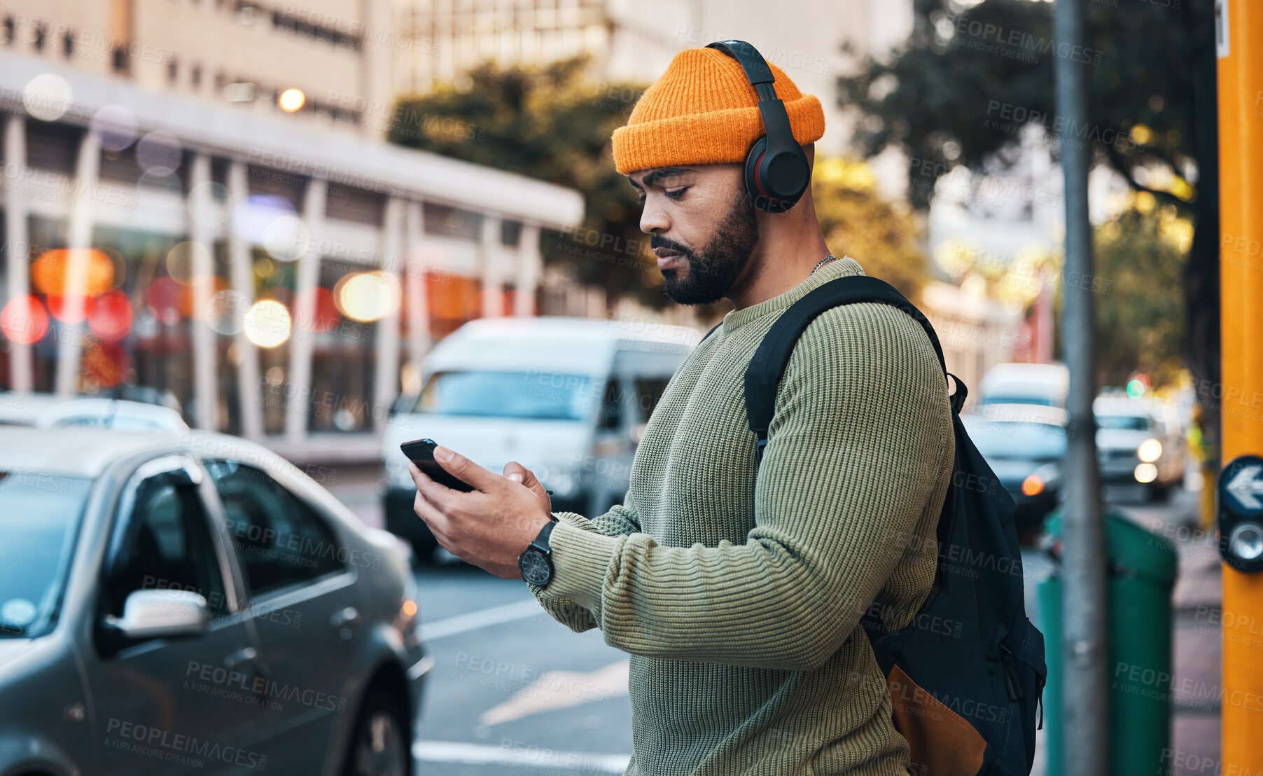 Buy stock photo Phone, headphones of student and man in city listen to music, sound or audio. Smartphone, radio and serious person in street for streaming podcast, typing on social media and reading email to travel