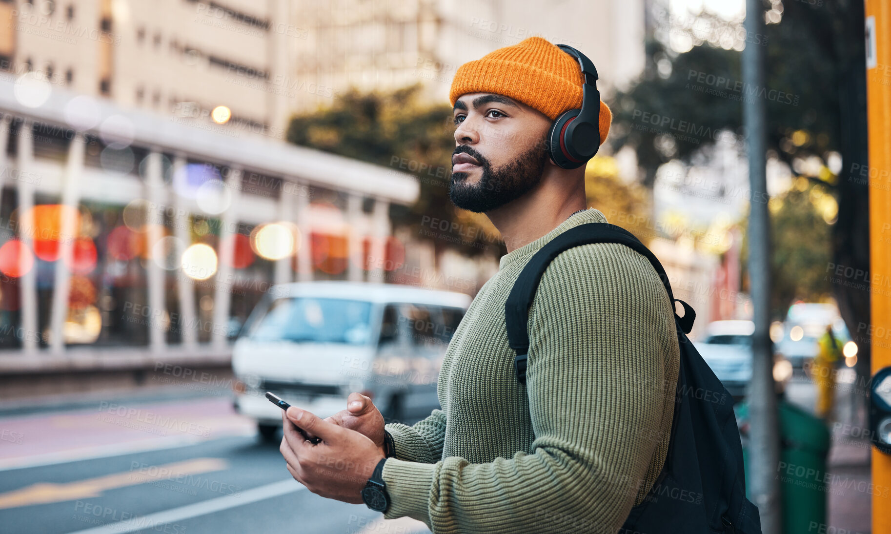 Buy stock photo Phone, headphones of student and thinking in city, listening to music or sound . Smartphone, radio and serious man in street for streaming podcast, typing on social media and reading email to travel