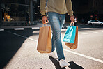 Man, legs and shopping bags in street of city, pedestrian or crosswalk for travel, shop or mall. Male person or shopper walking on road with paper bag for discount, sale or retail store in urban town