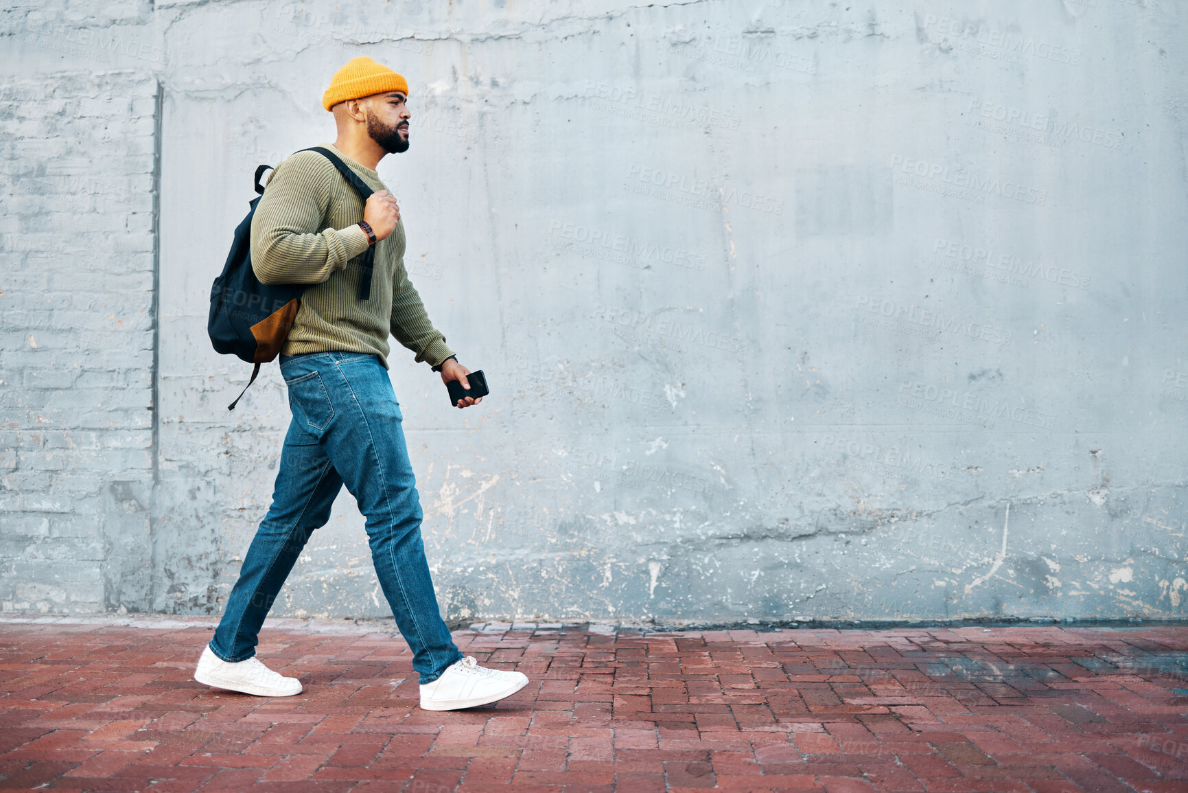 Buy stock photo Student, walking and travel with man on wall, mockup and space in urban, campus or street in town. University, person and commute on path, road or journey to college in city with phone or backpack