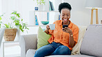 Coffee, woman and laugh with phone on sofa, reading social media post and mobile chat at home. Happy african person drinking tea, scroll multimedia connection and funny meme online with smartphone
