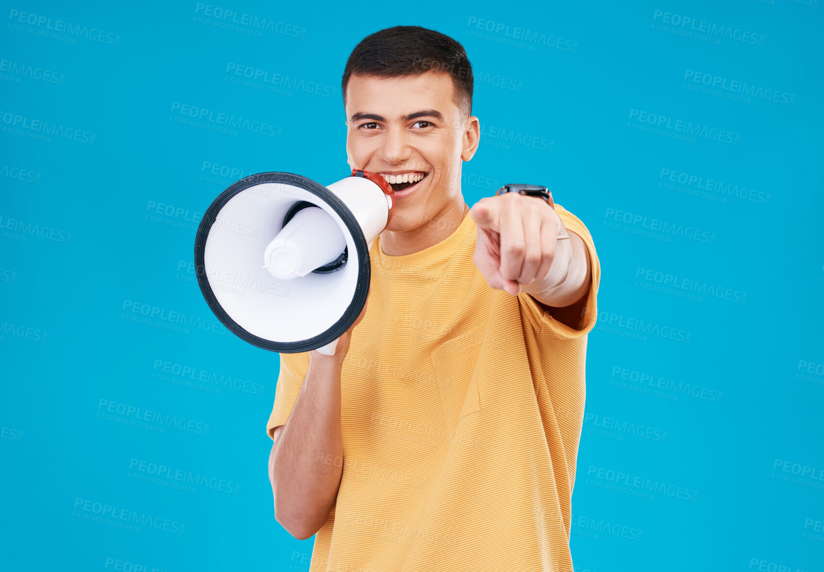 Buy stock photo Bullhorn, happy and portrait of man in studio pointing for announcement, speech or rally. Smile, protest and young person from Canada with megaphone for loud communication isolated by blue background