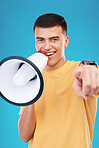 Megaphone, happy and portrait of man in studio pointing for announcement, speech or rally. Smile, protest and young person from Canada with bullhorn for loud communication isolated by blue background