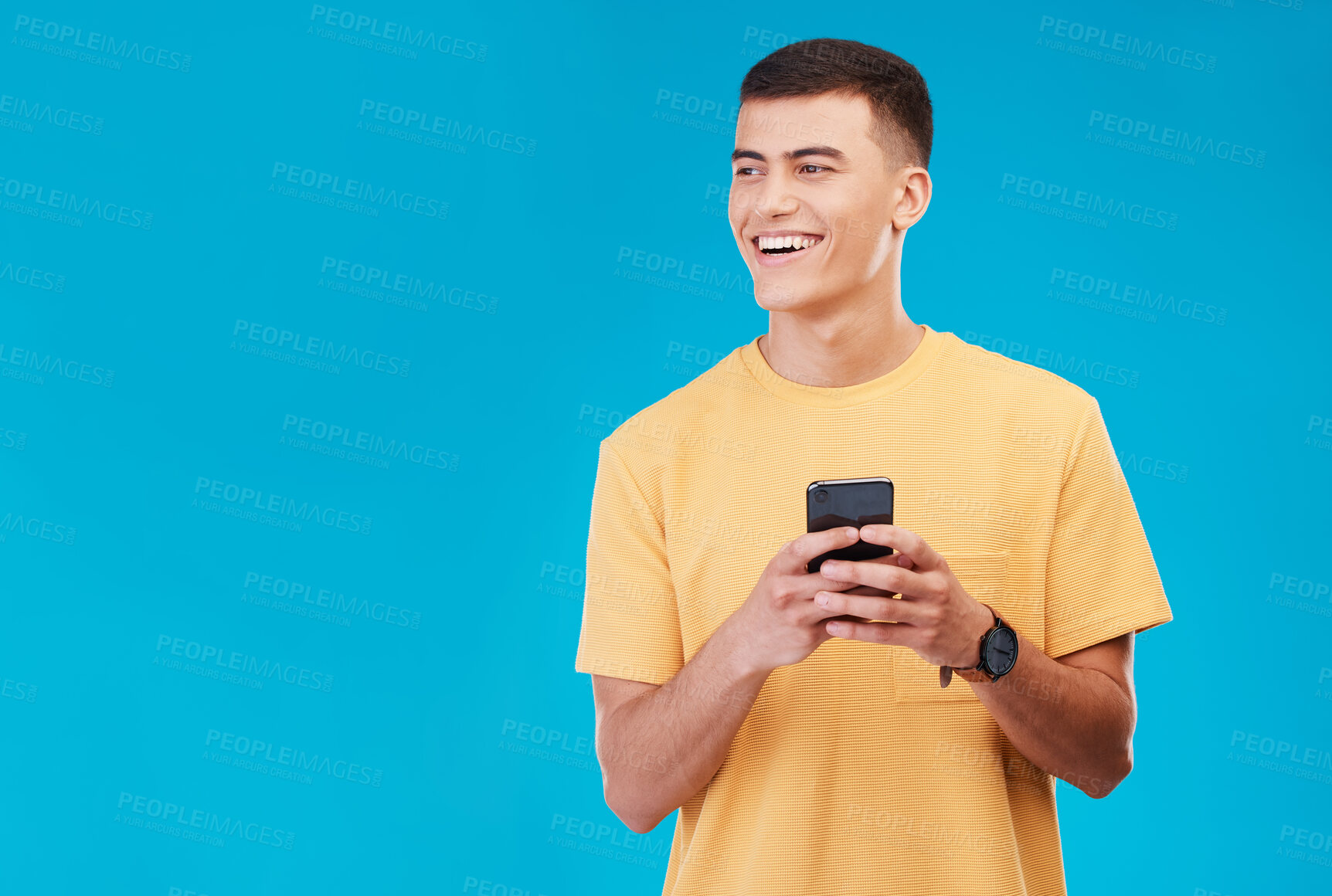 Buy stock photo Phone, smile and young man in studio networking on social media, mobile app or the internet. Happy, technology and male person from Canada scroll on website with cellphone isolated by blue background