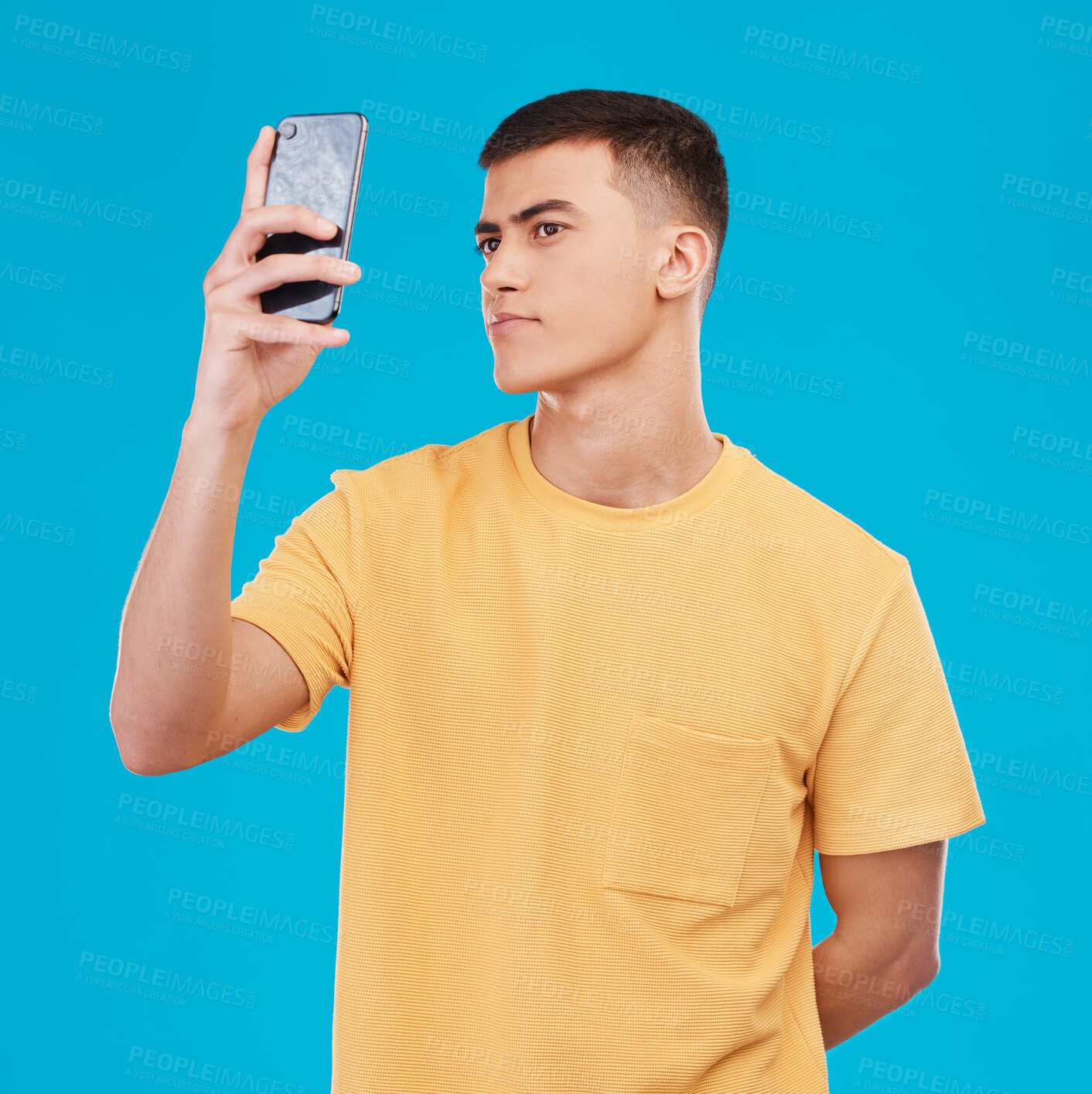 Buy stock photo Man, profile picture and selfie on phone in studio by blue background, influencer and fashion. Asian male model, pose for social media or blog post, technology and isolated wit smartphone in mockup