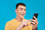 Phone, excited and young man in a studio scroll on social media, mobile app or the internet. Smile, happy and male person from Canada networking on website with cellphone isolated by blue background.