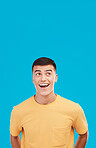 Man, face and customer with wow, surprised or open mouth expression in studio on blue background for sale. Fashion, emoji and person or guy on mock up space for deal or discount announcement or news 