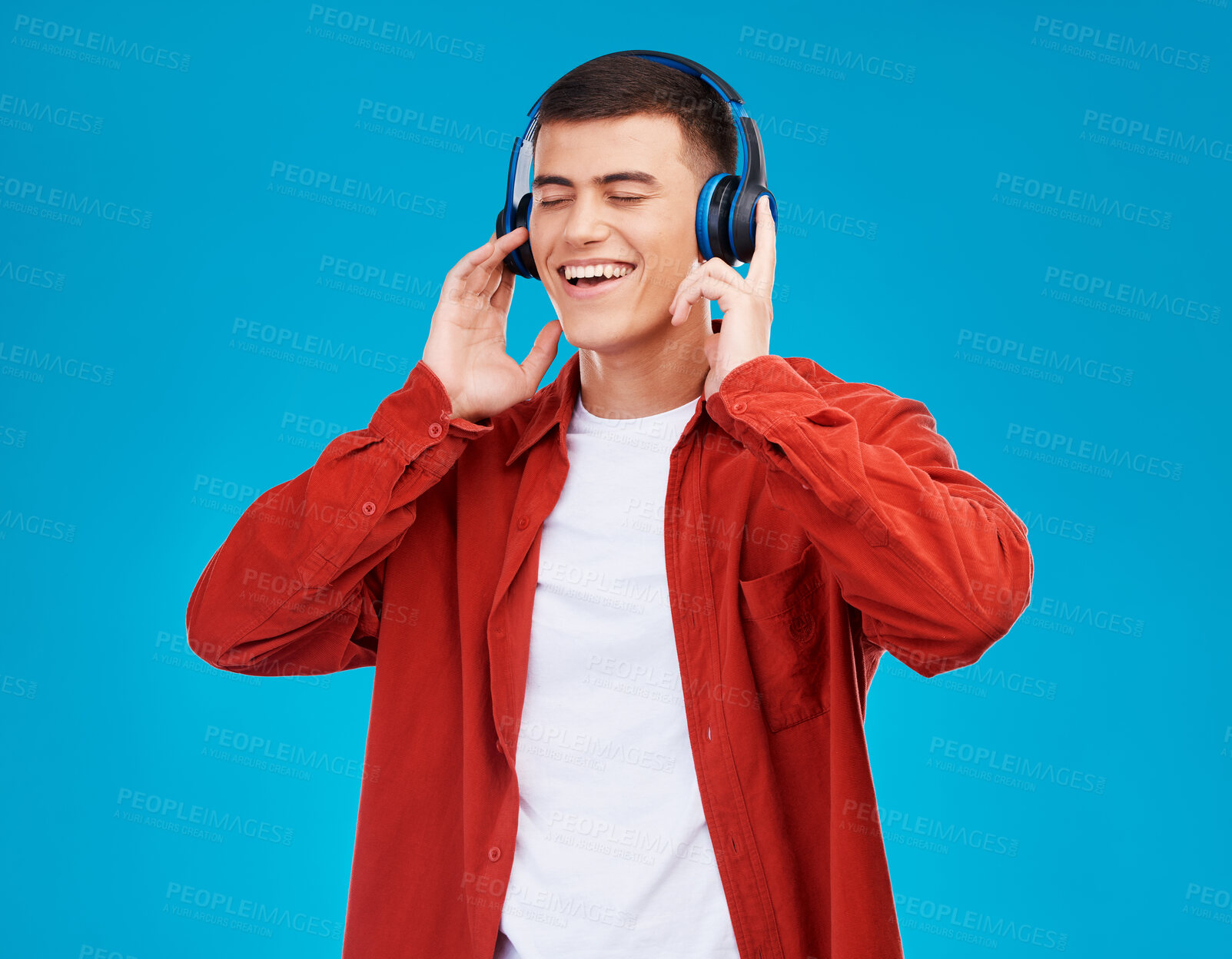 Buy stock photo Man, smile and headphones for streaming radio in studio by blue background. Asian person, listening and chilling to song, radio and audio or hearing a funny podcast, technology and sound for joy