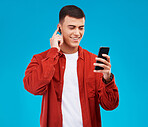 Man, earpods and smile with phone for music streaming in studio and happy by blue background. Asian male model, searching online and smartphone while listening to radio, song and audio or podcast