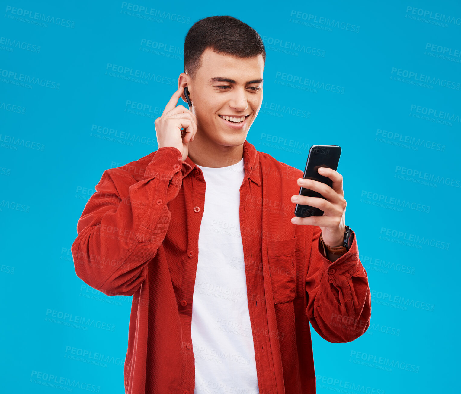 Buy stock photo Man, earphones and smile with phone for music streaming in studio and happy by blue background. Asian male model, searching online and smartphone while listening to radio, song and audio or podcast