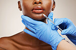 Closeup, black woman and needle with plastic surgery, healthcare and cosmetics on a white studio background. African person, girl and model with injection, hands and gloves with wellness and skincare