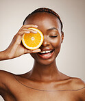 Black woman, orange fruits and skincare in studio for vitamin c, vegan dermatology and cosmetics on brown background. Happy model, citrus diet and nutrition for natural beauty, organic facial or glow