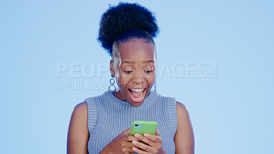 Buy stock photo Shock, phone and black woman in a studio with good news on the internet for winning a bet. Happy, surprise and excited young African female model scroll on cellphone isolated by blue background.