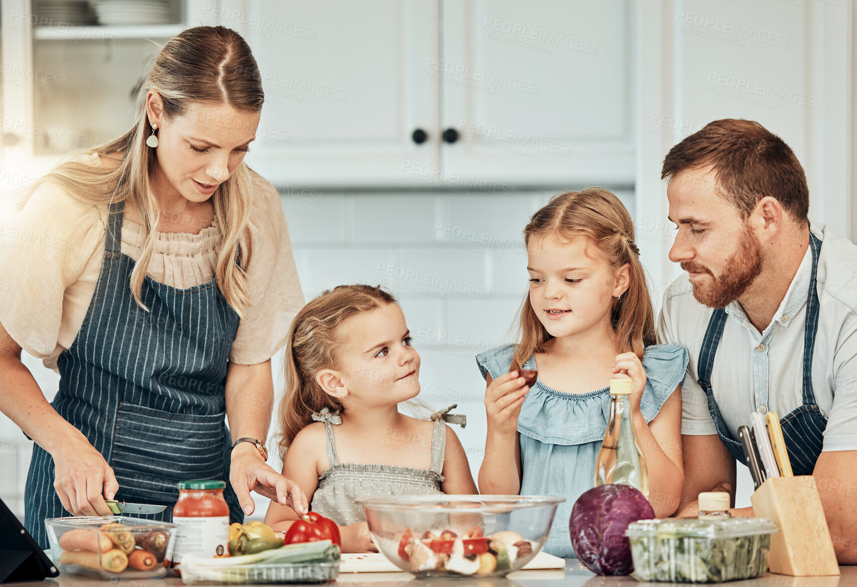 Buy stock photo Happy family in kitchen, cooking together with children and teaching, learning and nutrition with parents. Mom, dad and girl kids help making healthy food in home with care, support and love at lunch