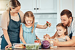 Family in kitchen, cooking together with children and teaching, learning and nutrition with parents. Mom, dad and girl kids help making healthy food in home with care, support and love at happy lunch