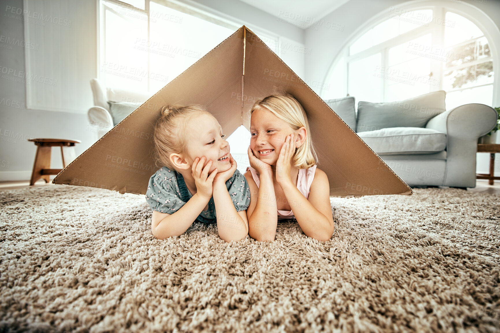 Buy stock photo Smile, kids and cardboard for insurance with girl sisters on the floor of the living room at home. Security. family or children and young siblings on a carpet in their house for safety with flare